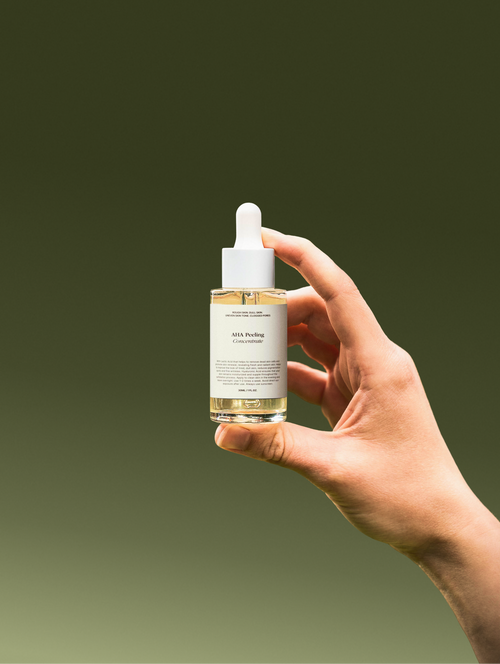 Hand holding a skincare dropper bottle with a gradient green background